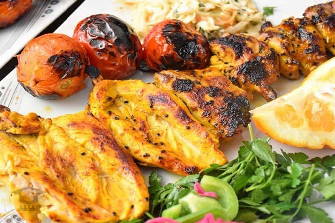 مواد اولیه تازه و باکیفیت برای تهیه جوجه کباب خانگی شامل تکههای مرغ، پیاز، فلفل دلمهای، ماست و زعفران